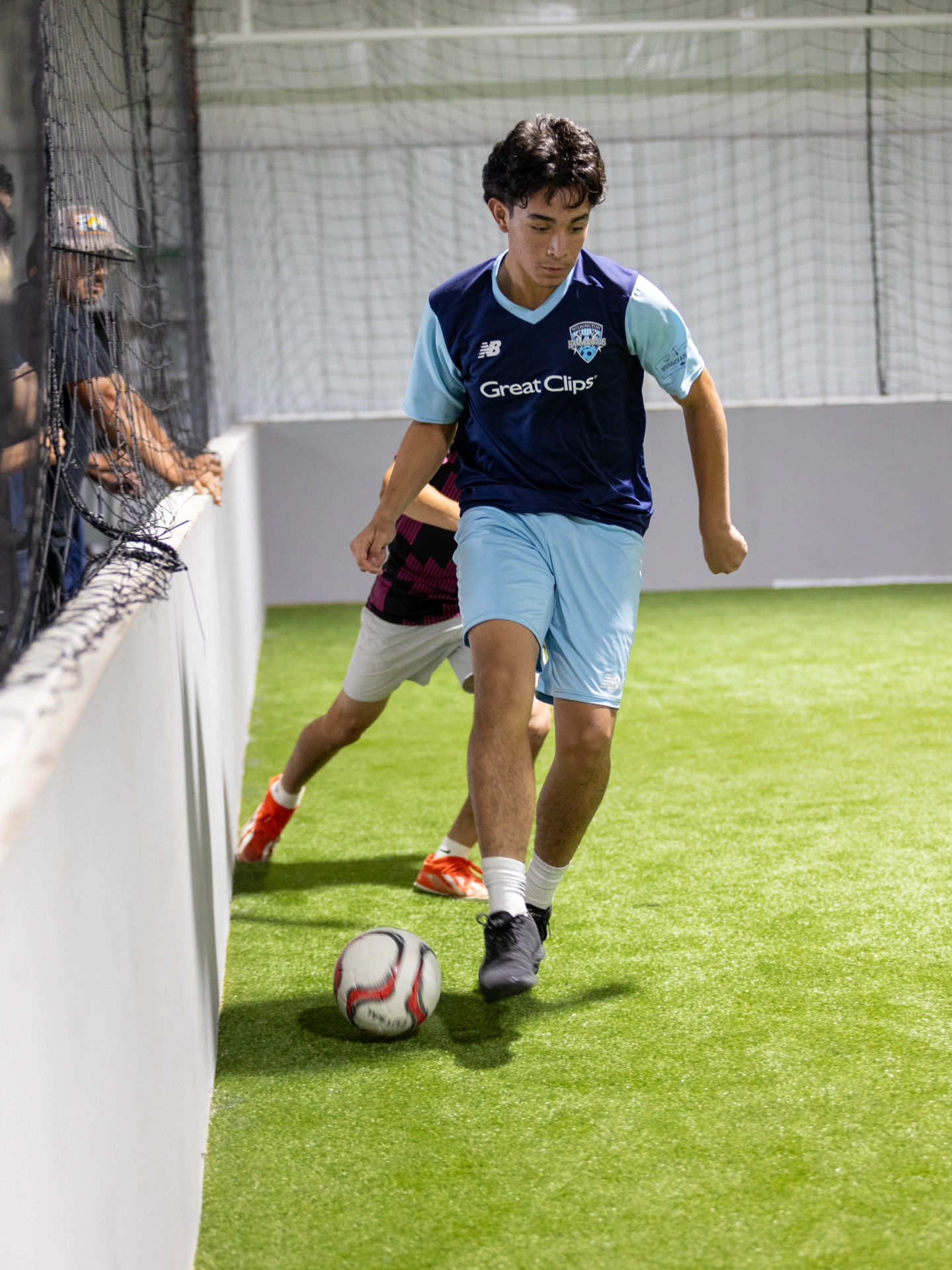 Close-up of a soccer cleat controlling a ball on indoor turf